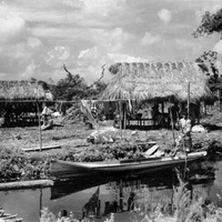 Seminole_village_-_Man_poling_a_dugout_canoe_by_a_village.jpg